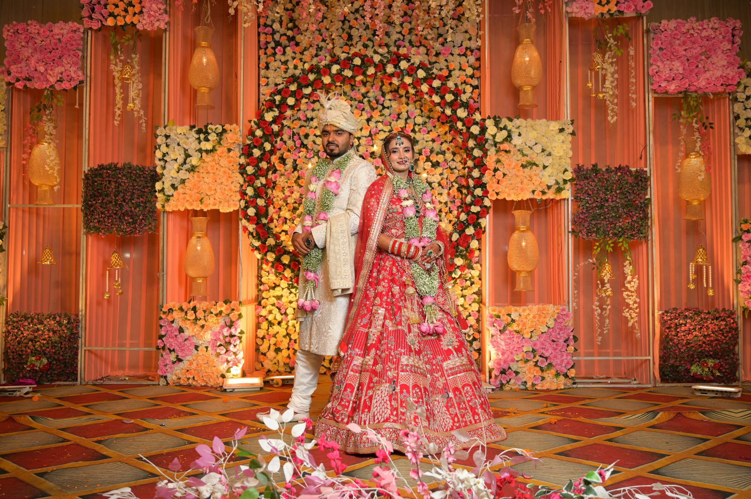 Elegant Indian couple posing at their wedding ceremony with floral decor background.