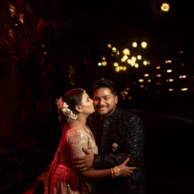 Elegant couple posing in traditional attire under ambient night lighting.